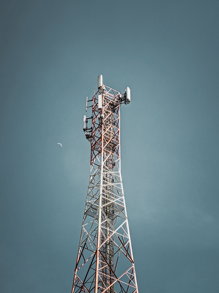 gallery-1 A tall telecommunication tower against a clear blue sky, symbolizing modern communication infrastructure.