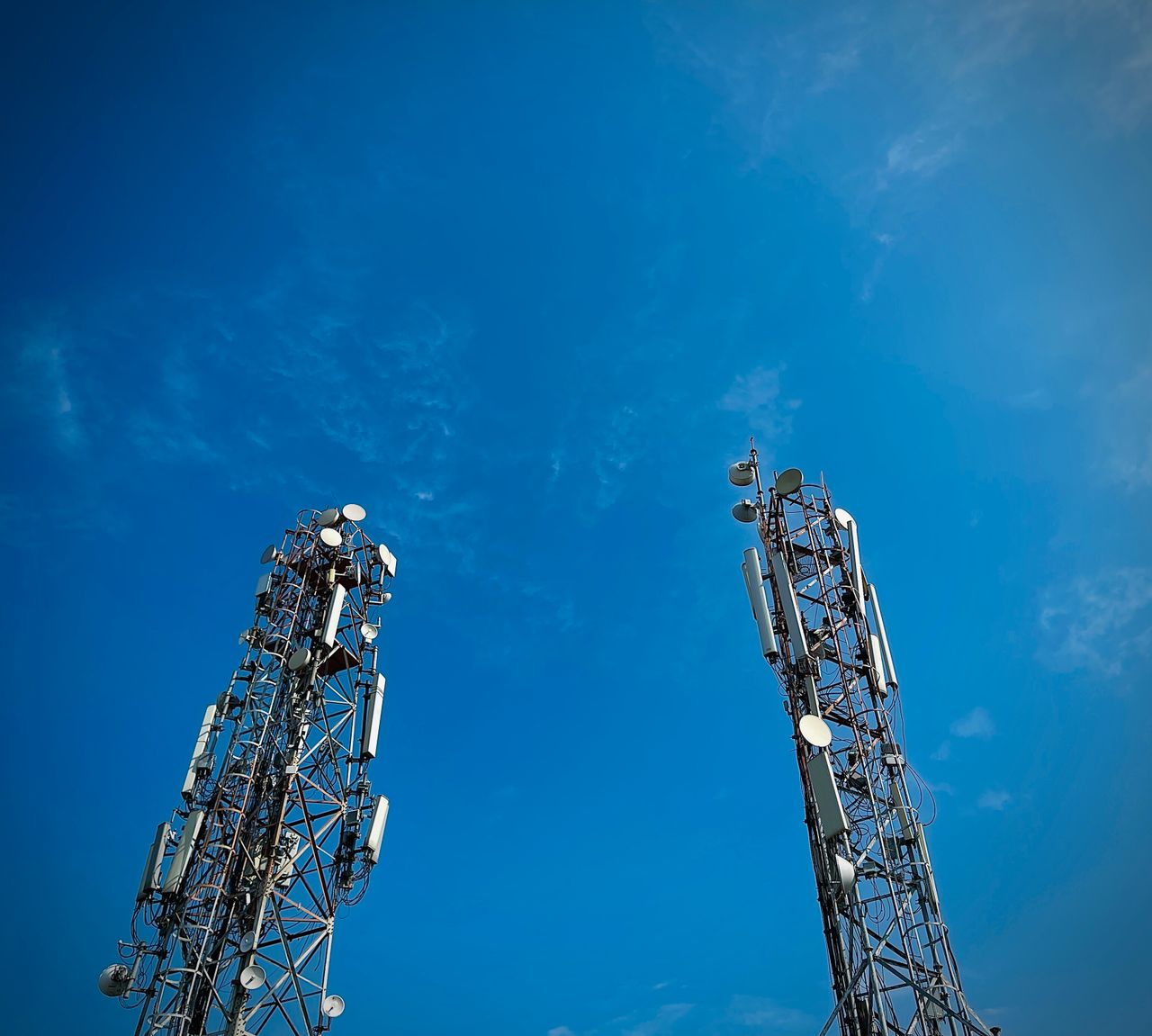 why-choose-us Two telecommunication towers standing against a vibrant clear blue sky, showcasing modern communication technology.
