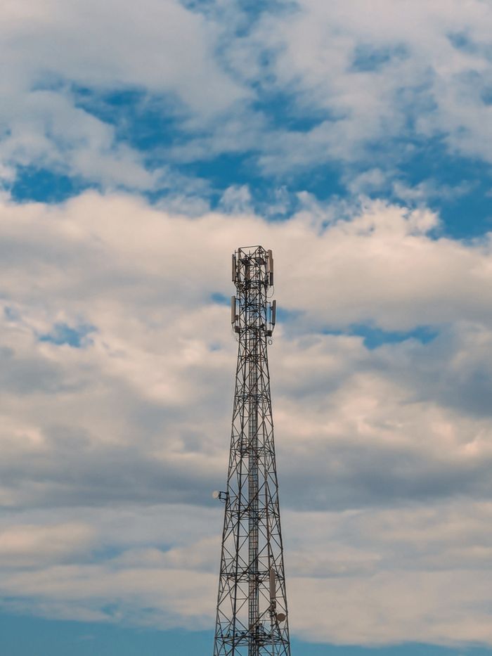 gallery-6 A tall cell tower set against a backdrop of blue sky with scattered clouds.
