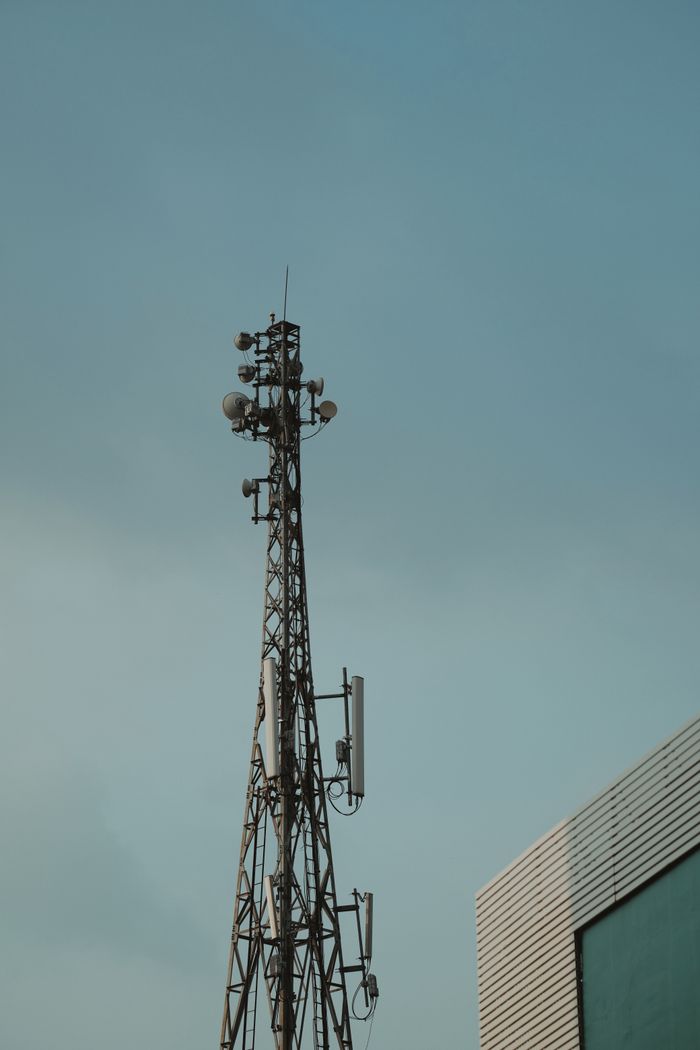 services-03 A tall metal telecommunication tower stands against a clear blue sky.