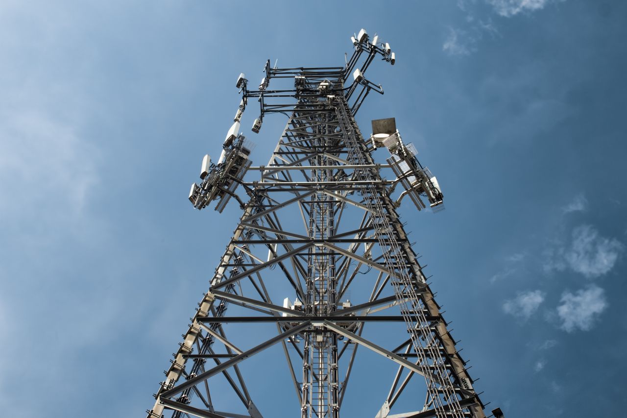 services-01 A low-angle shot of a tall metal communications tower with multiple antennas against a clear blue sky.