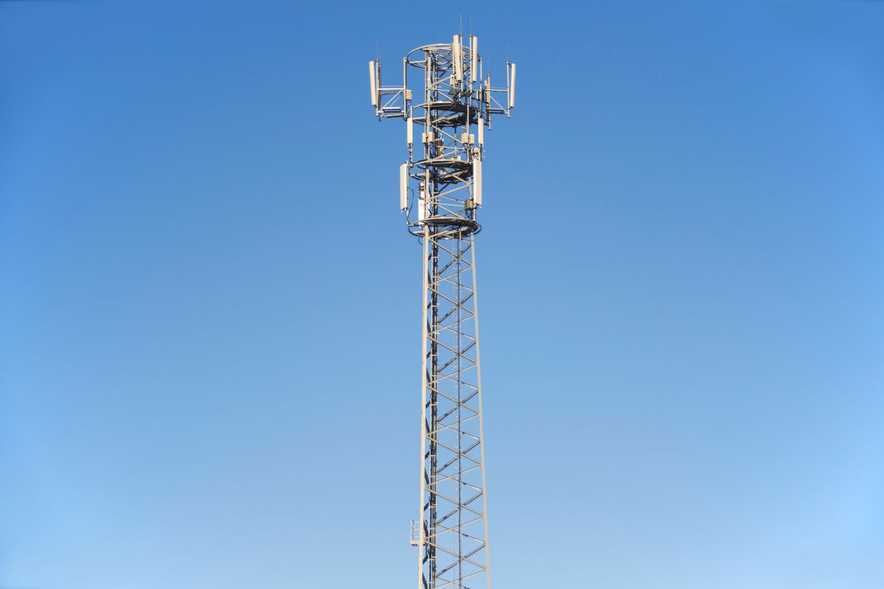 our-experience A tall cell tower set against a clear blue sky, representing modern communication technology.